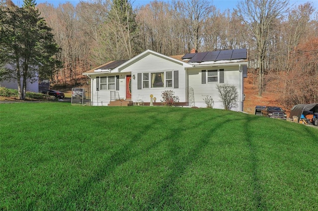 ranch-style house featuring roof mounted solar panels and a front lawn
