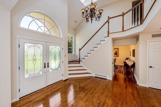 entrance foyer featuring visible vents, a baseboard radiator, high vaulted ceiling, and wood finished floors