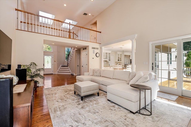 living area with visible vents, a high ceiling, recessed lighting, wood finished floors, and stairs