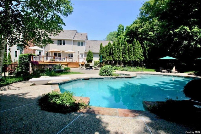 outdoor pool featuring a patio area, a wooden deck, and a diving board