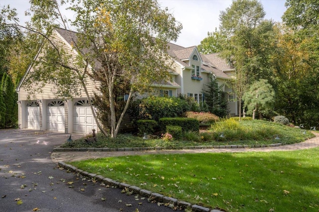 view of front of property featuring aphalt driveway, a garage, and a front lawn