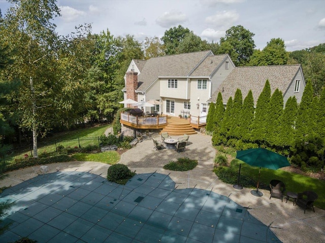 rear view of property with a patio area, fence, a deck, and a fenced in pool
