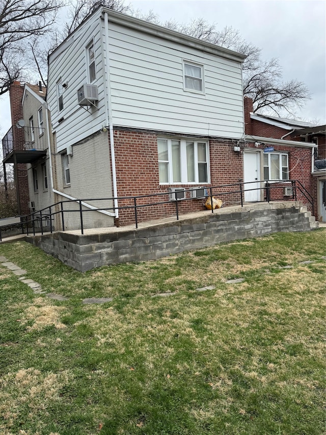 rear view of property featuring cooling unit, brick siding, and a yard