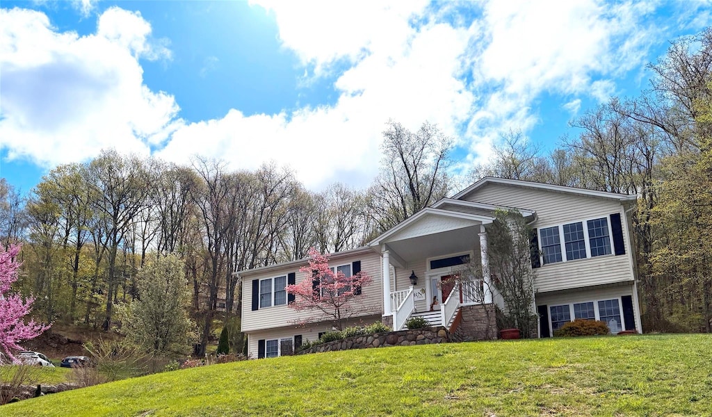 split foyer home featuring a porch, a front lawn, and stairs