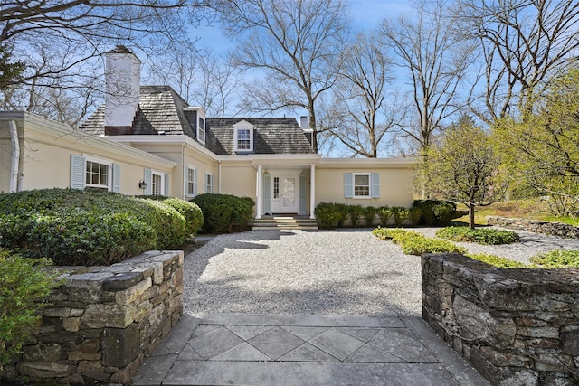 cape cod home with a chimney and stucco siding