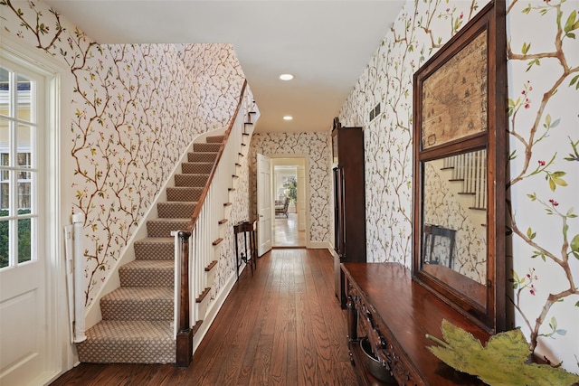interior space with wallpapered walls, a healthy amount of sunlight, stairs, and dark wood-style flooring
