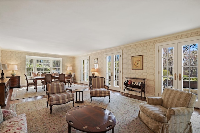 living area featuring french doors, hardwood / wood-style floors, wallpapered walls, and plenty of natural light