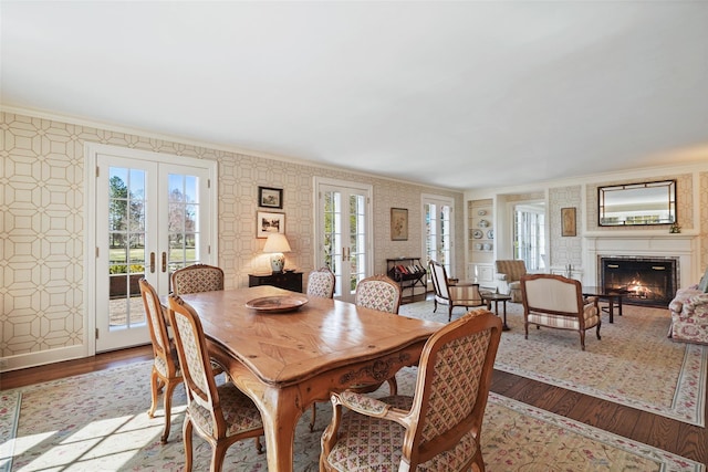 dining space with crown molding, wood finished floors, and wallpapered walls