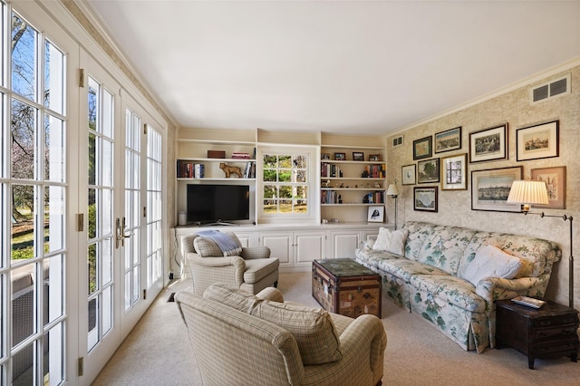 living area with french doors, visible vents, carpet, and ornamental molding