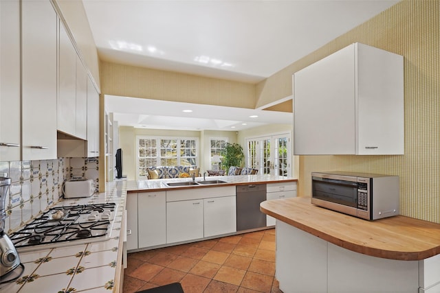 kitchen with white cabinets, a sink, tasteful backsplash, wooden counters, and appliances with stainless steel finishes