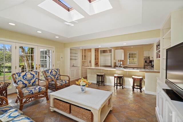 living room featuring french doors, built in features, a skylight, and recessed lighting