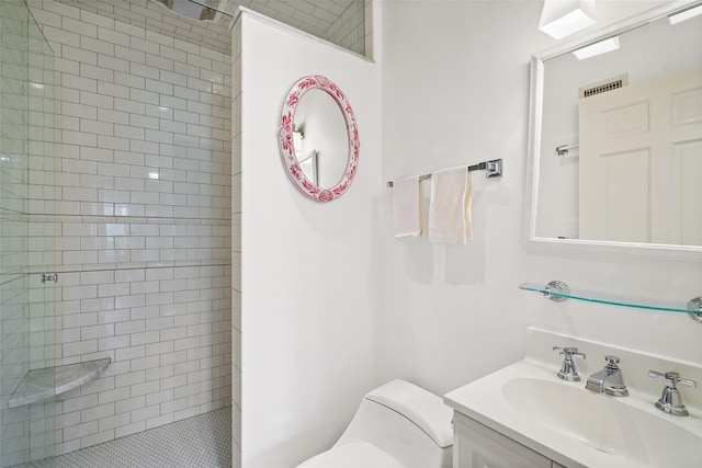 bathroom featuring a tile shower, toilet, and vanity