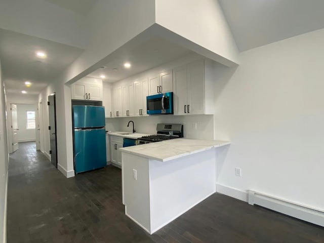 kitchen with a baseboard heating unit, gas range, dark wood-style floors, freestanding refrigerator, and a peninsula
