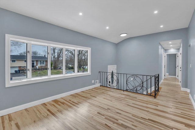 unfurnished room with baseboards, lofted ceiling, wood finished floors, and attic access