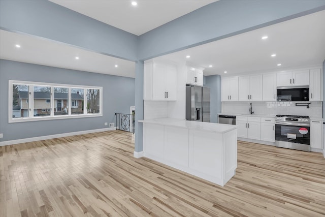 kitchen featuring white cabinetry, tasteful backsplash, appliances with stainless steel finishes, baseboards, and light wood-style floors