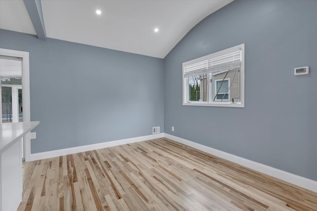 unfurnished room featuring light wood-style flooring, baseboards, vaulted ceiling, and visible vents