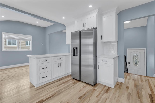 kitchen with decorative backsplash, stainless steel refrigerator with ice dispenser, a peninsula, and light wood finished floors