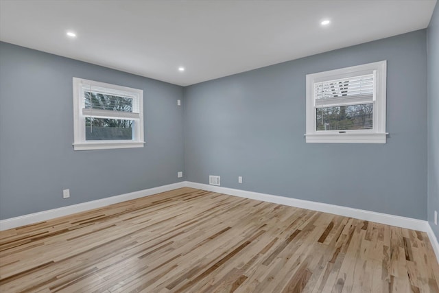 unfurnished room featuring wood finished floors, plenty of natural light, and visible vents