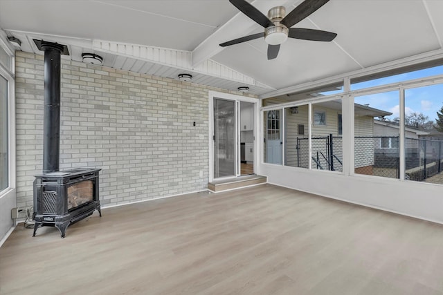sunroom featuring beamed ceiling and a wood stove