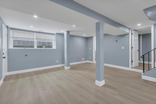 finished basement featuring light wood-style flooring, baseboards, stairs, and recessed lighting