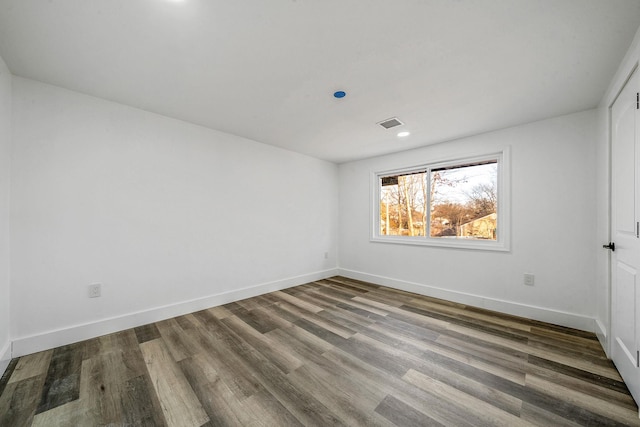 empty room featuring baseboards, visible vents, and wood finished floors
