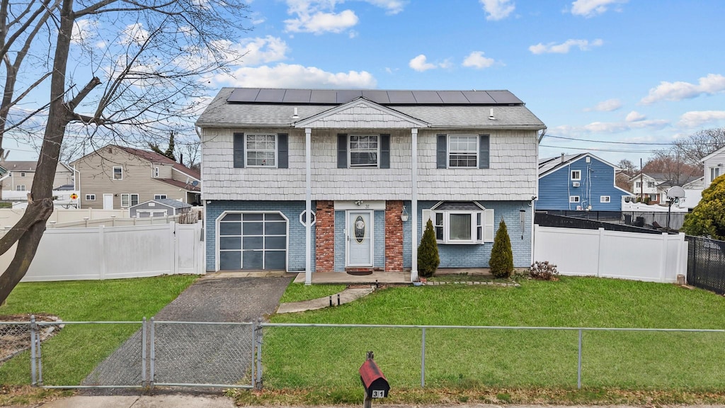 31 Olive St, Central Islip, NY 11722 - view of front of property featuring driveway, a fenced front yard, a gate, a front yard, and solar panels