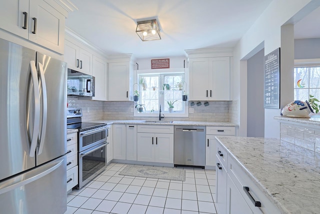 kitchen featuring light tile patterned floors, a sink, white cabinetry, decorative backsplash, and appliances with stainless steel finishes