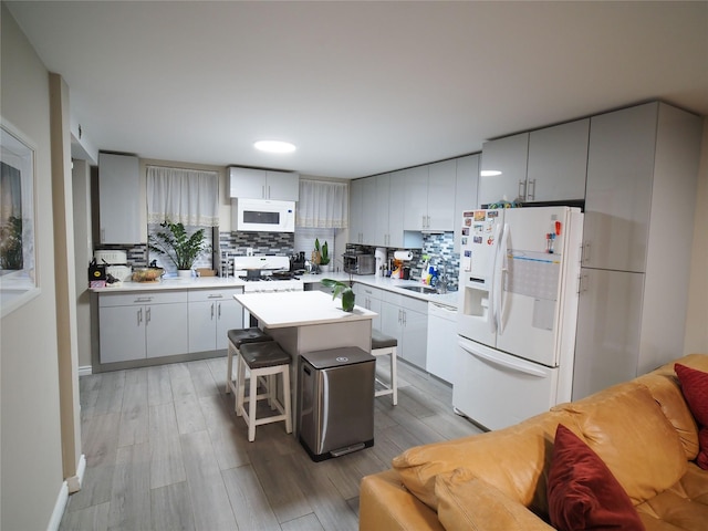 kitchen with white appliances, decorative backsplash, a kitchen island, and a breakfast bar area