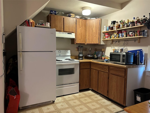 kitchen with light floors, under cabinet range hood, white appliances, and brown cabinetry