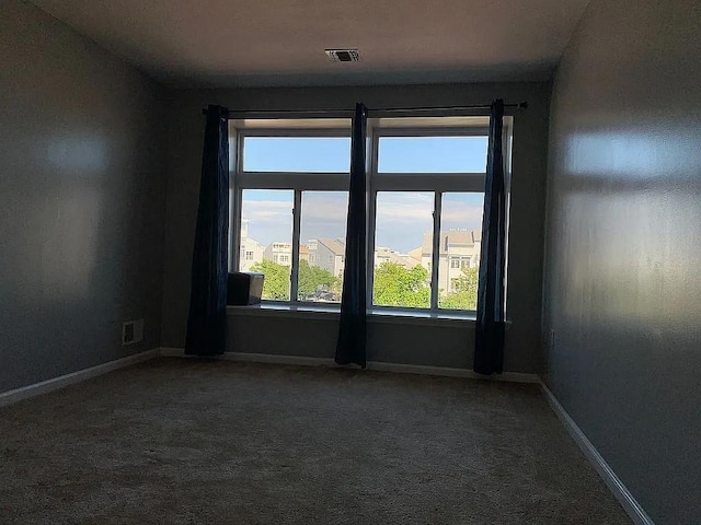 carpeted empty room featuring baseboards