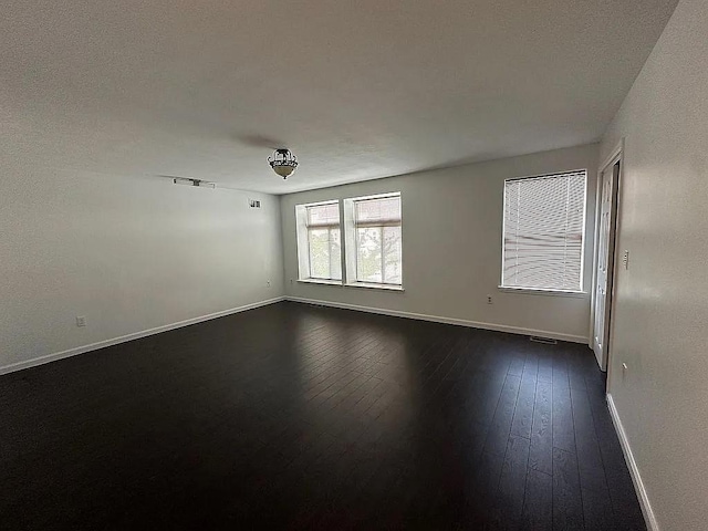 empty room with baseboards and dark wood-style flooring