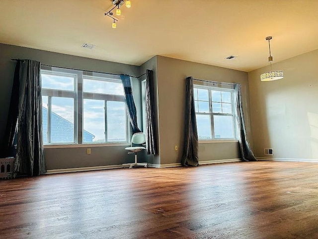 spare room featuring healthy amount of natural light, wood finished floors, and baseboards