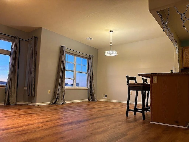 unfurnished dining area featuring dark wood-type flooring and baseboards