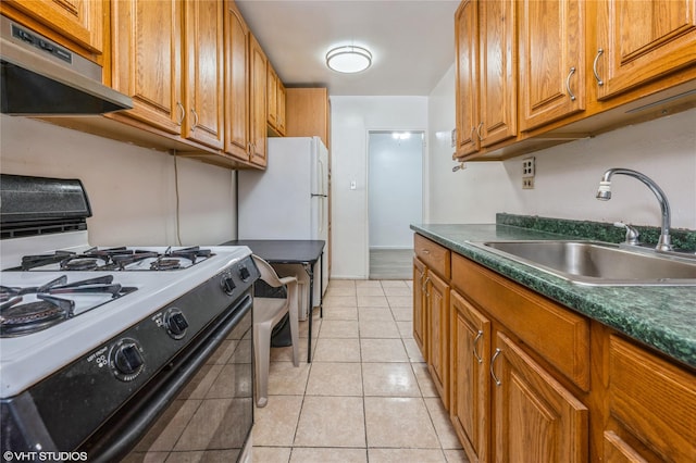 kitchen featuring under cabinet range hood, dark countertops, a sink, and gas stove