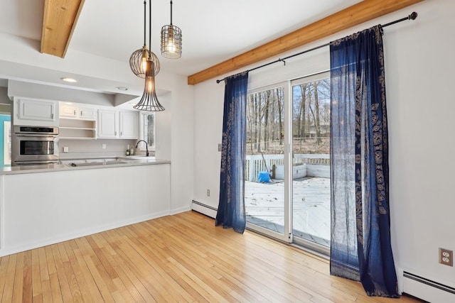 kitchen featuring white cabinets, a baseboard heating unit, stainless steel oven, and a sink