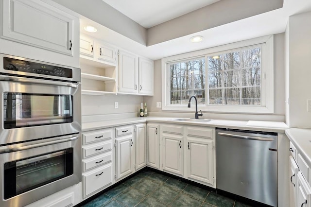 kitchen with light countertops, stainless steel appliances, white cabinetry, and a sink