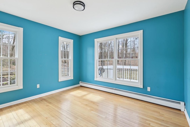 unfurnished room featuring baseboards, baseboard heating, and hardwood / wood-style flooring