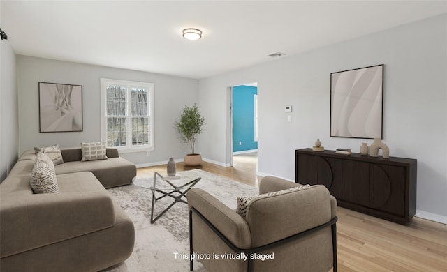 living area featuring baseboards, visible vents, and light wood-style floors