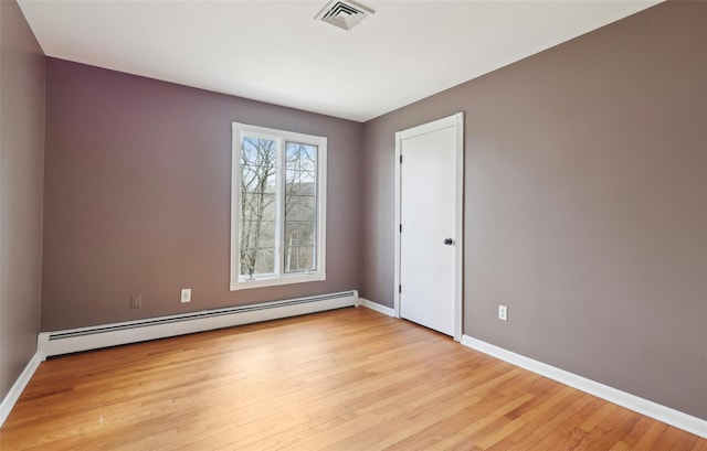 spare room with light wood-style floors, baseboards, a baseboard heating unit, and visible vents