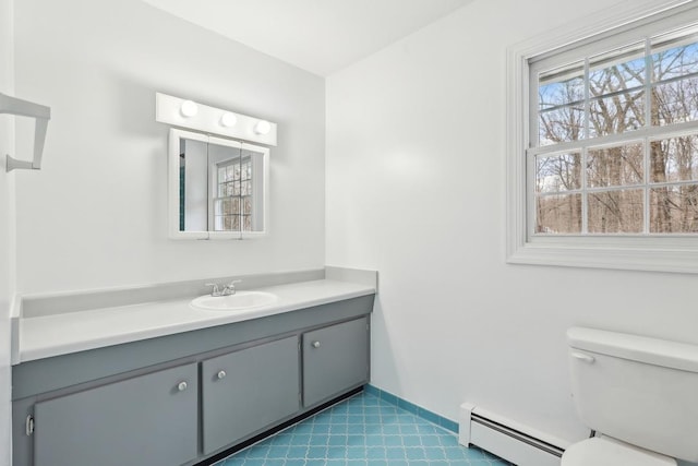 half bath featuring vanity, a baseboard heating unit, and toilet