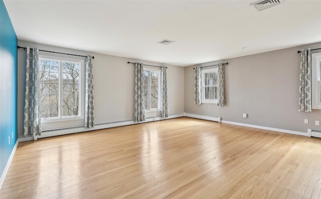 empty room with visible vents, light wood-style floors, baseboards, and a wealth of natural light