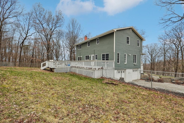 back of property featuring a lawn, fence, a chimney, and a deck