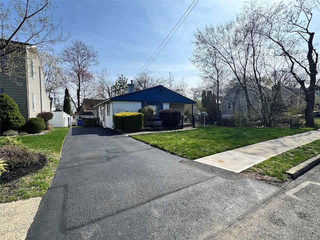 view of property exterior featuring aphalt driveway, fence, and a lawn