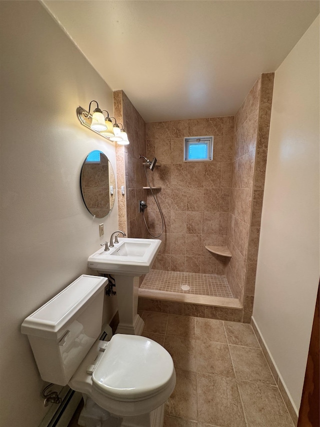 bathroom with toilet, a sink, and tiled shower