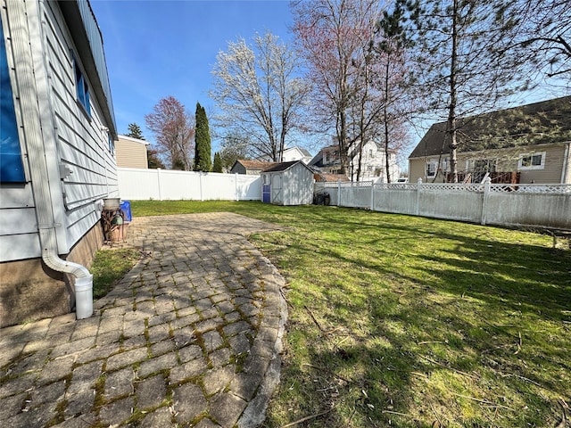 view of yard with a fenced backyard, an outbuilding, a patio area, and a storage shed