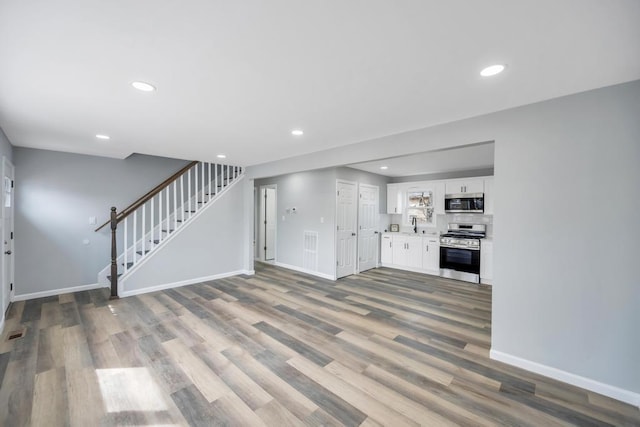 81 New Ave, Wyandanch, NY 11798 - unfurnished living room with recessed lighting, baseboards, stairs, and wood finished floors
