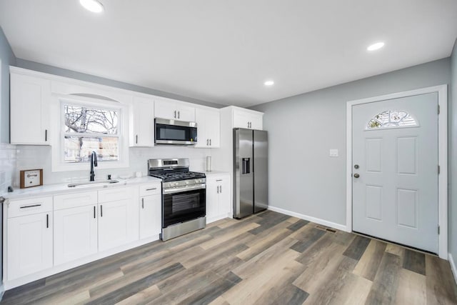 81 New Ave, Wyandanch, NY 11798 - kitchen with light countertops, decorative backsplash, a sink, appliances with stainless steel finishes, and wood finished floors