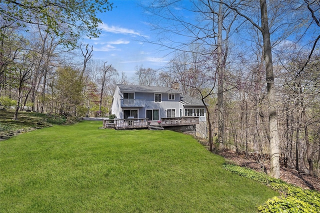 back of property with a lawn, a deck, a balcony, and roof with shingles