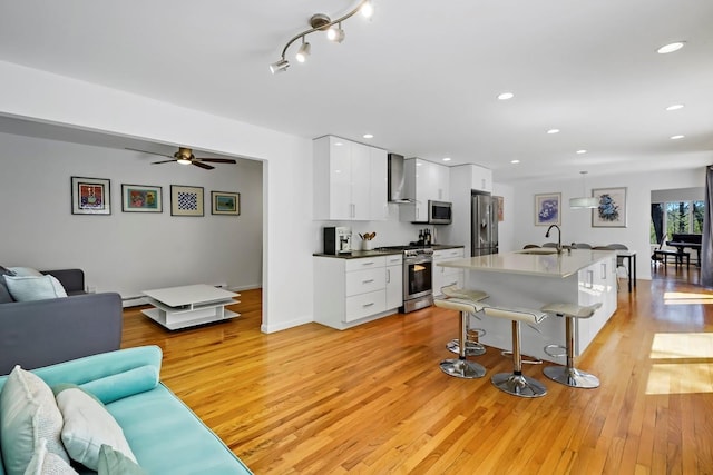 living room featuring recessed lighting, baseboards, ceiling fan, and light wood finished floors
