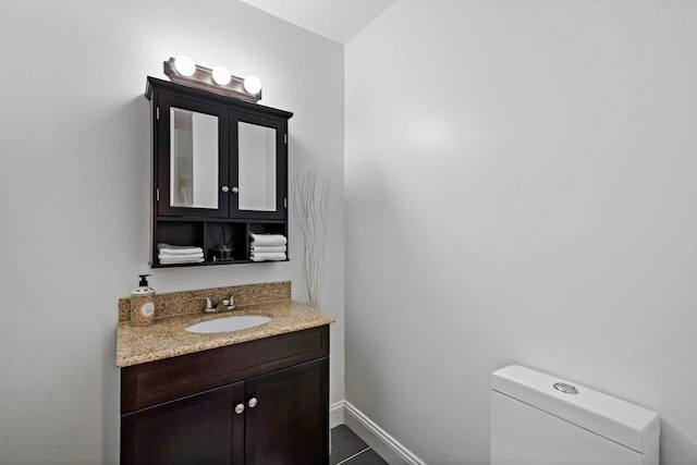 bathroom featuring toilet, baseboards, and vanity